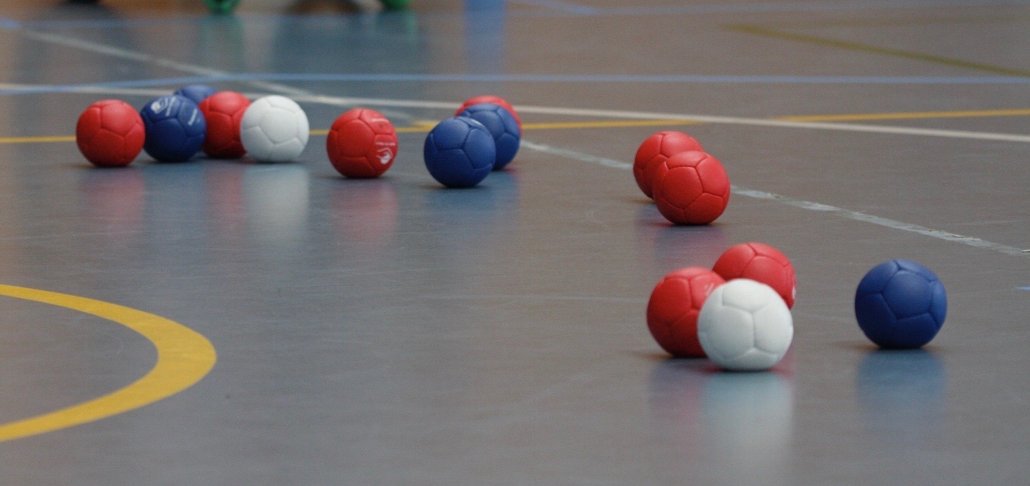 An iamge of some balls on the floor of a sports area.
