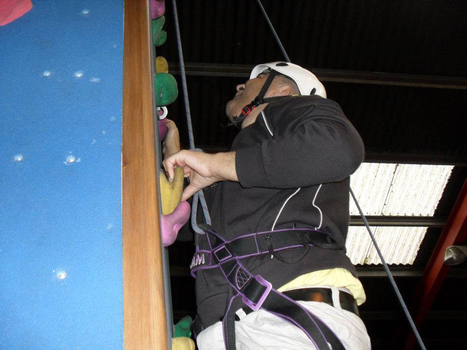 A person climging up a coloured rock climbing wall.
