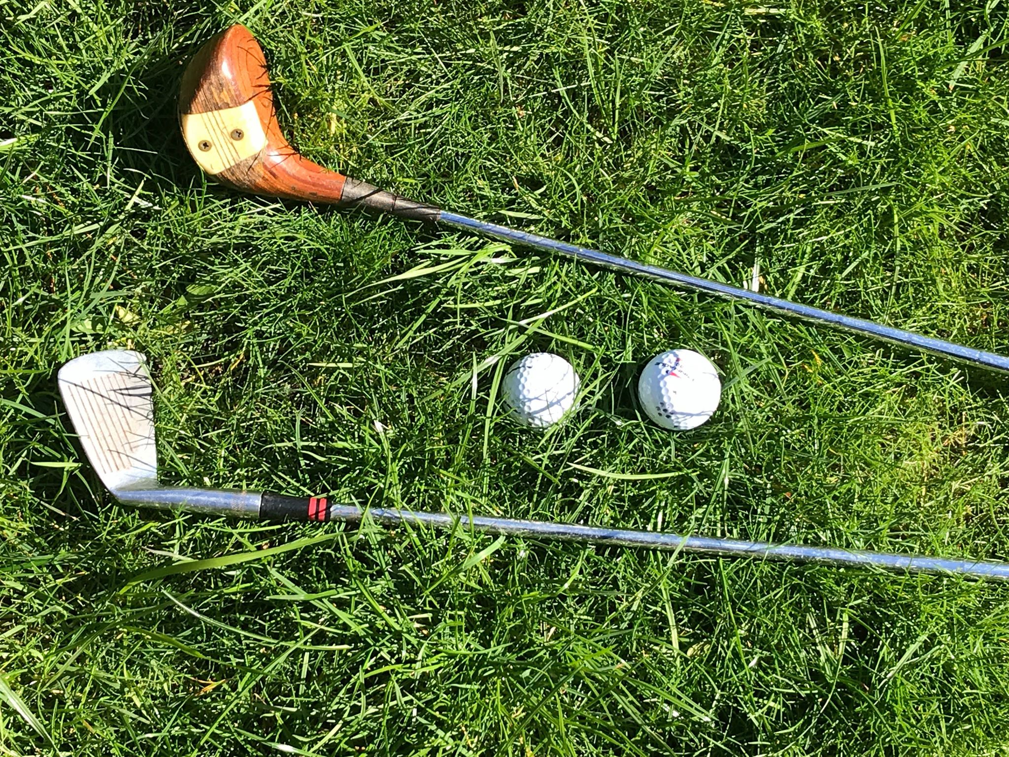 A set of golf clubs and balls on the grass.