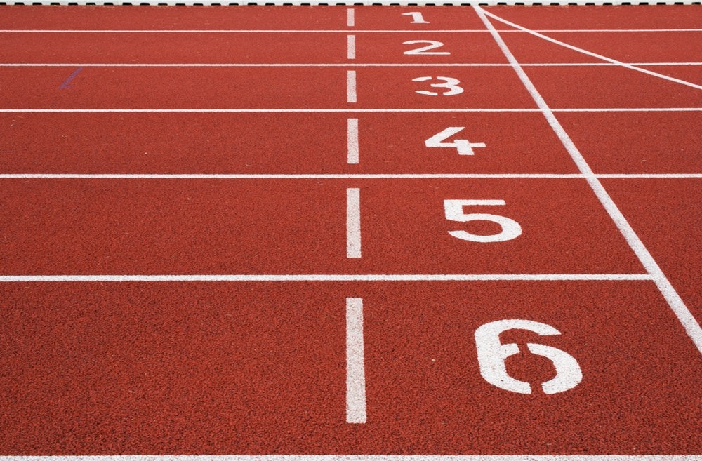 An image of a red running track, with the lanes marked out with numbers.